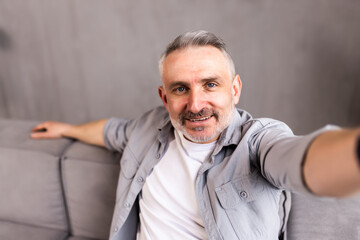 middle-aged man in his sofa takes a picture in selfie at home