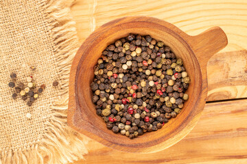 Mixture of four pepper peas with wooden cup on wooden table, macro, top view.