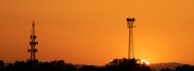 Panorama of sunset behind two communication towers 