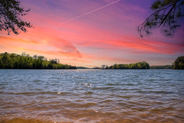 Naklejka na ściany i meble a gorgeous spring landscape at Lanier Point Park with rippling blue water surrounded by lush green trees and plants with powerful cloud at sunset at Lake Lanier in Gainesville Georgia USA