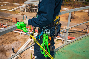 Closeup male worker standing on tank male worker height roof tank knot carabiner rope access safety