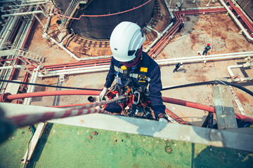 Focus top view male worker down height tank roof rope access safety inspection of thickness storage...