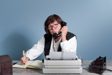 A secretary woman from the past at work. Vintage concept. Table with telephone and typewriter.