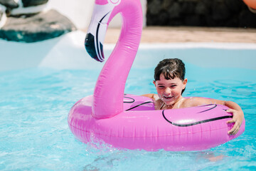 Girl floating in pool with pink inflatable flamingo