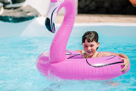Girl floating in pool with pink inflatable flamingo