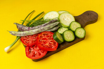 half-top view sliced fresh vegetables tomatoes squashes and cucumbers with greens and beans on yellow desk vegetable ripe fresh food meal health