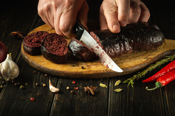 A knife in the cook's hand for cutting blood sausage for a very tasty dinner. Cooking a national...