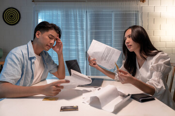 Stressed and confused Asian couple calculating expenses on invoices.