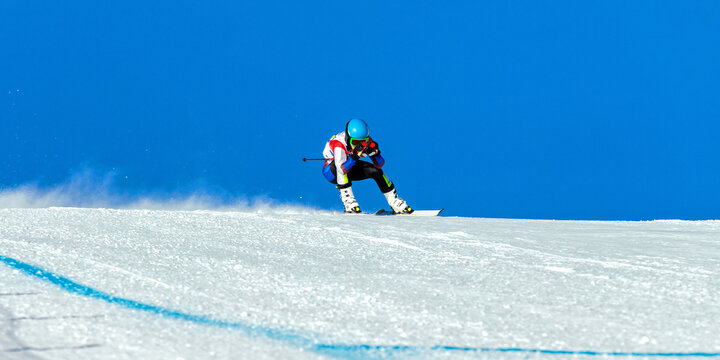 male ski racer on alpine skiing track downhill, snowy slope on blue sky background, winter sports games