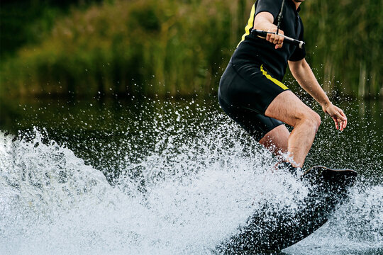 man wakeboarding behind motorboat on lake, extreme water sports, summer vacation