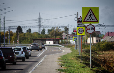 A series of road signs stands on a busy highway on a summer day