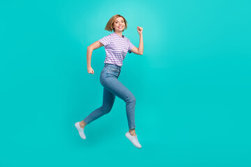 Fototapeta na wymiar Full length photo of satisfied adorable girl dressed stylish t-shirt denim pants jump run at sale isolated on turquoise color background