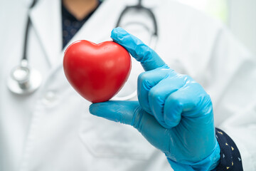 Doctor holding a red heart in hospital ward, healthy strong medical concept.