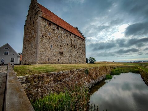 Majestic view of Glimmingehus overlooking a tranquil river situated in a picturesque grassy meadow