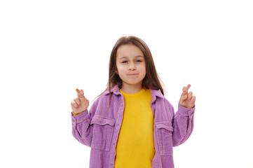 Portrait of 5-6 years Caucasian nice little child girl with beautiful long hair, standing with crossed fingers and hopes for good luck and her dreams come true, isolated over white background.