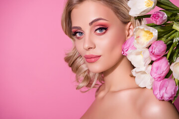 Naklejka premium Stunning girl model studio portrait posing over decorated tulips backdrop bright makeup isolated pink pastel background