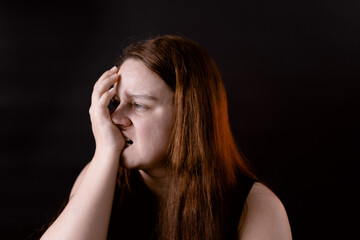 Crazy young woman biting finger. Female portrait isolated on black. Self harm, pain, suffering. Broken unhappy girl. Mentally unhealthy person. Human emotions, facial expression concept.