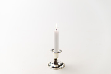 burning candle inside silver candlestick on white background steel lamp flame