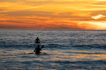 Surfer and kayaker at Sunset, San Clemente beach, Orange County, California, USA