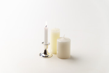 Fototapeta na wymiar burning candle with other candles on white background lamp steel flame fire