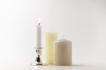 burning candle with other candles on white background metallic lamp steel flame fire