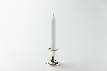 white candle inside silver candlestick on white background flame lamp fire steel metallic