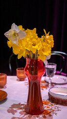 bukiet kwiatów narcyzy w czerwonym dzbanku stojącym na stole 