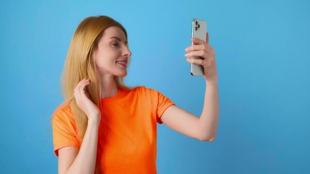 Selfie, pose and woman with phone, peace sign for social media post. Fashionable lady with mobile smartphone posing smiling, taking profile picture, studio shot isolated on blue background