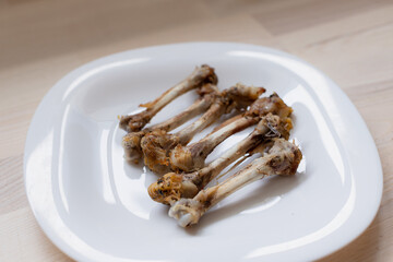 Multiple chicken bones on a white plate