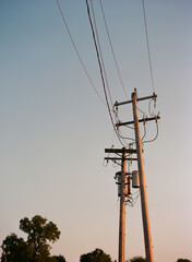 Utility poles and power lines lean different directions during blue hour on a cloudless evening.