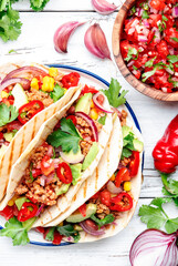 Tacos with beef, corn, red beans, tomato salsa sauce and red onions in corn tortilla on plate. Mexican cuisine. White table background, top view