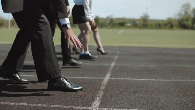 Concept of business competition, goals, achievements. Businessmen stand on starting line of stadium preparing for the race, close-up of the legs
