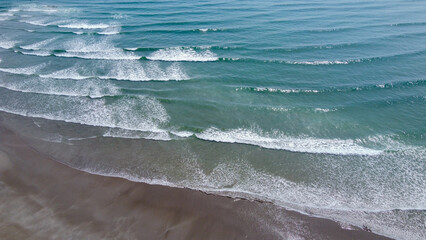 Wet coastal sand and sea waves, top view. Sandy beach and ocean tide. Seascape. Aerial view, waves