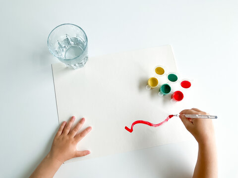 small child draws with paints and brush on white table. fathers day