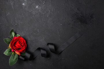 top view of black bow with red flower on dark background funeral death