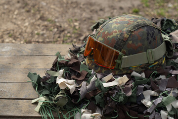 Military helmet with tactical goggles on camouflage net. Ukrainian war