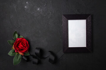 top view of picture frame with black bow and red flower on the dark background death funeral