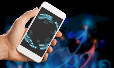 Human hand holding mobile phone on dark background.