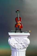 miniature violin perched on a roman pedestal