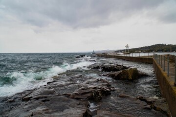 Wooden pier at the splashing waves of the sea, surrounded by a rocky shore
