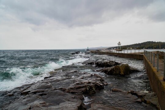 Wooden pier at the splashing waves of the sea, surrounded by a rocky shore