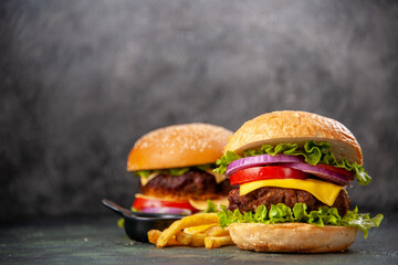 Delicious sandwiches fries on wooden cutting board on the left side on dark mix color background