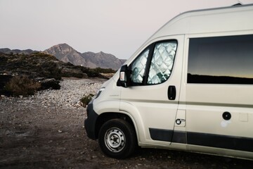Fototapeta na wymiar Selective focus of a white van with mountain rocks in the background