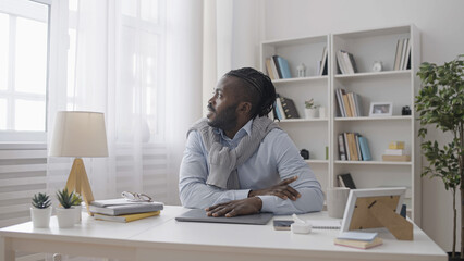 A male office worker finishes his work, closes the laptop, and enjoys the view from the window