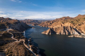 Aerial view of a river running through a rugged, arid landscape with blue sky in the background