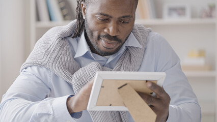 Smiling businessman taking a break from work to look at family photo on desk