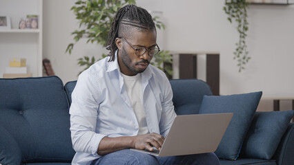 Busy programmer in eyeglasses working on laptop at home, freelance job