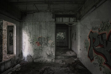 Gloomy interiors of an abandoned building. Empty room. Graffiti on the walls. Concrete room....