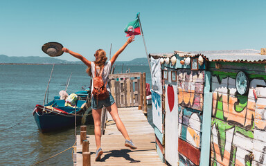Obraz premium Carrasqueira pier in Portugal-ancient wooden pier with happy woman tourist traveling in Europa