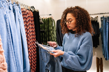 Black young female looking at price of jeans in shop